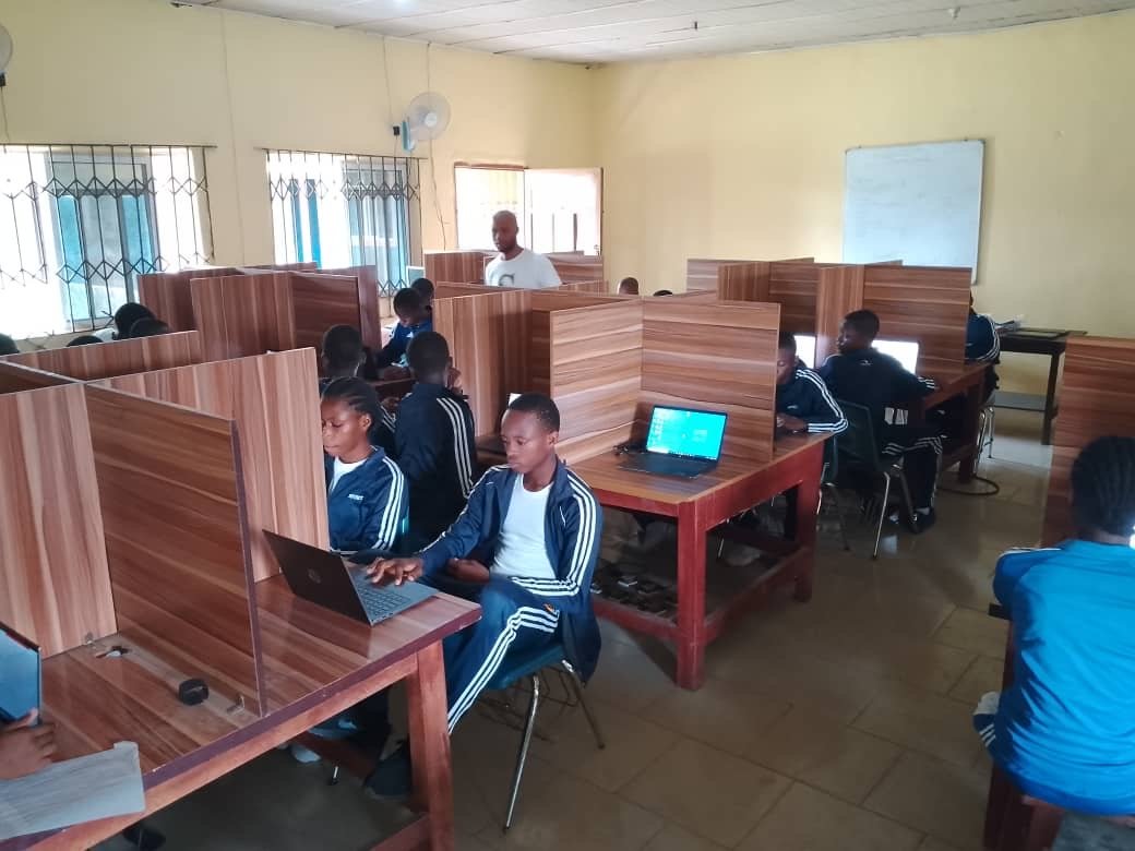 Young people using laptops in a computer room in Nigeria.