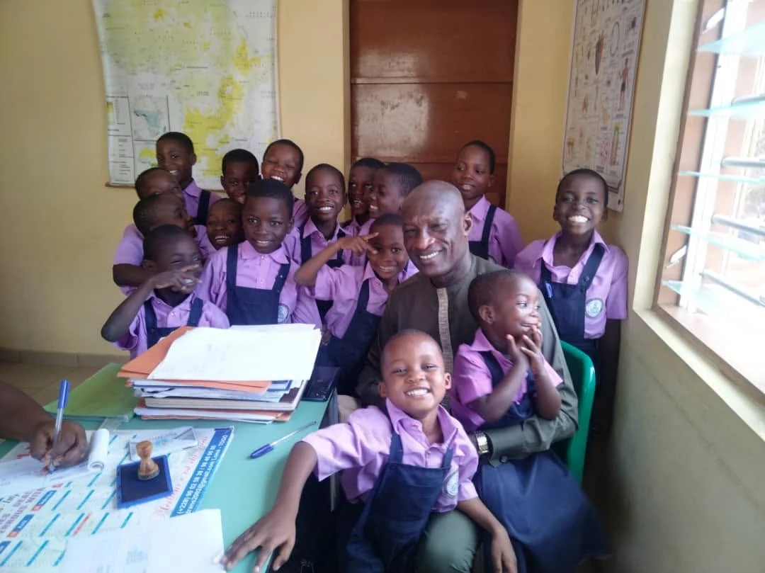 Pupils in uniform gathered around an adult in their classroom